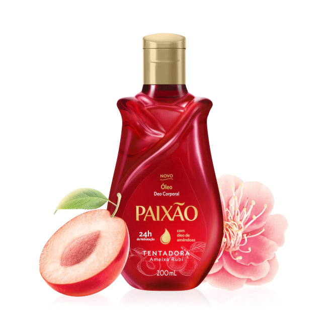 Paixão Tentadora Ameixa Rubi Körperöl mit Mandelöl, rote 200-ml-Flasche mit goldenem Verschluss neben einer aufgeschnittenen Pflaume und einer rosa Blüte
